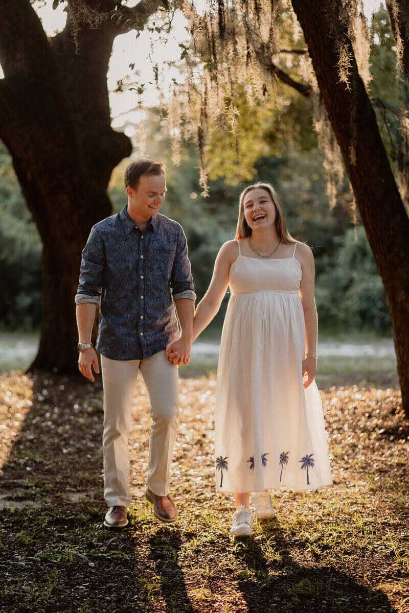 Couple laughing in golden hour light beneath spanish moss